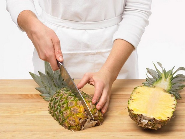 Целый неочищенный ананас разрежьте вдоль на четыре части, разрезая листья и основание.